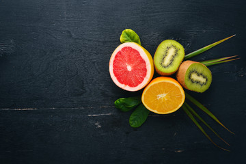 Kiwi, orange and grapefruit, fresh fruits. On a wooden background. Top view. Free space for text.