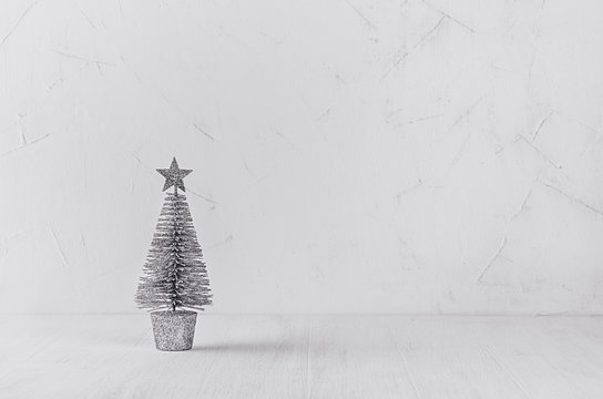 Silver christmas tree on white shabby plaster and wood background. Christmas home interior, decoration, copy space.