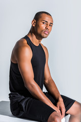 young african american sportsman sitting and looking at camera on grey