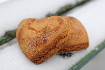 Homemade cookies with sugar and cinnamon in the form of hearts on a background of snow