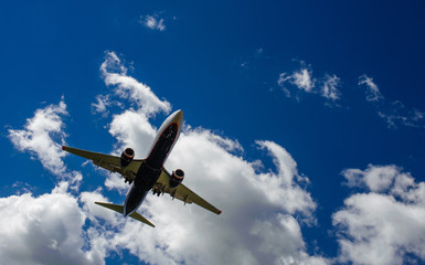 Fototapeta na wymiar The plane on a background of blue sky and white clouds.