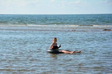 M&auml;dchen sitzt in einem Schwimmreifen im Meer, macht mit den H&auml;nden Friedens  Zeichen