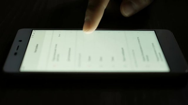Use of smartphone in hands of close-up, menu scrolling is side view. Hand Scrolls smartphone settings.