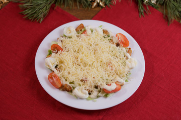 Greens, tomatoes, eggs, cheese, sauce and croutons salad on a white plate on a red background.