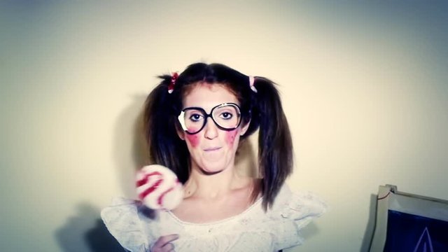 Waving nightmare: a woman dressed up like a little girl, with nerdy glasses, licking a lollipop while looking at the camera - zoom in, she says some nonsense words. Funny comedic shot.
