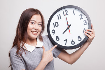 Young Asian woman point to a clock.