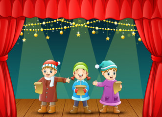 Three kids singing christmas carols on stage