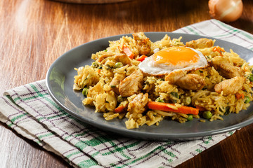 Fried rice nasi goreng with chicken egg and vegetables on a plate.