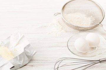 Eggs, flour, butter on a white table. Place for text.