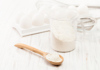 Fototapeta na wymiar Flour in a wooden spoon on a white table in the kitchen