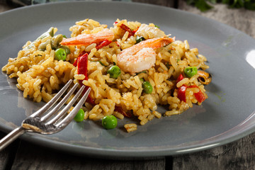 Traditional seafood paella with shrimp, fish and chicken seved in plate.