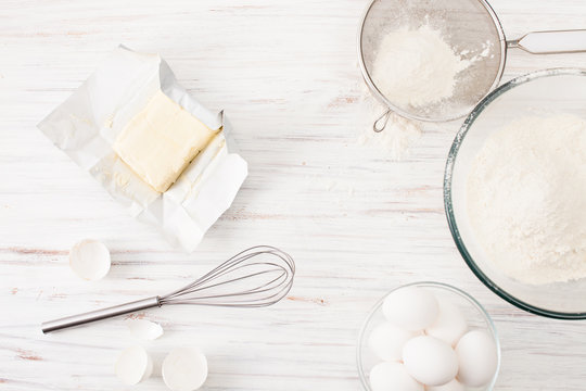Eggs, flour, butter on a white table. Place for text.