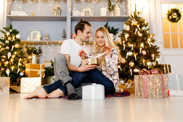 Obraz na płótnie Canvas Sweet couple opening Christmas gifts