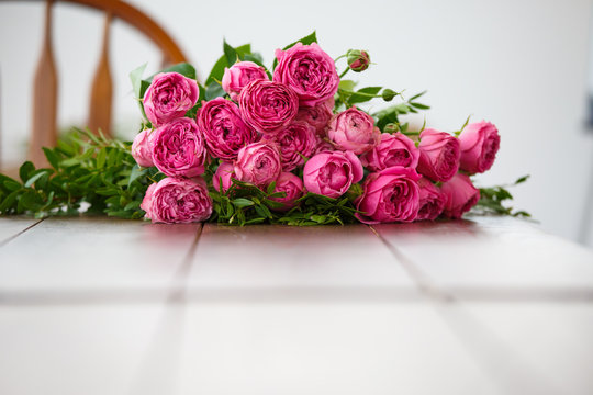 Image of bouquet of pink peonies on white wooden table
