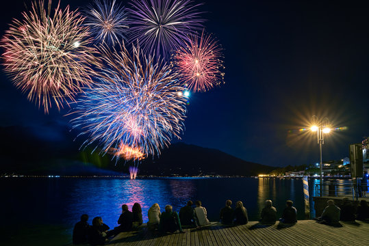 Crowd watching fireworks and celebrating. Beautiful firework display for celebration on the Garda Lake,italy,Brightly Colorful Fireworks