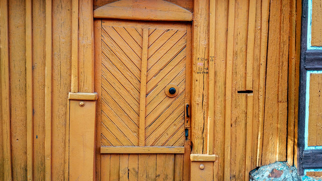 Background fence in summer with door, in autumn wooden boards with yellow wooden boards, brightly orange background. In the summer in the city entrance door to the house.