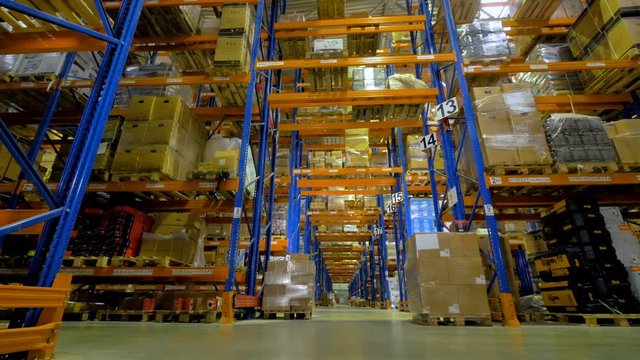 A long warehouse corridor between rows of metal racks. 