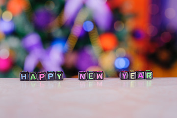 the inscription "happy new year" lined with colorful little letters on the background of Christmas decorations
