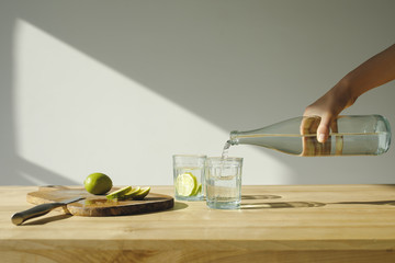 cropped image of woman pouring mineral water into glass