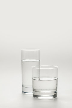 Two Different Glasses With Calm Water Isolated On White