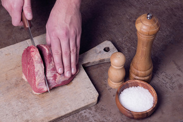 Butcher cutting beaf meat on kitchen. Food background. Top view.