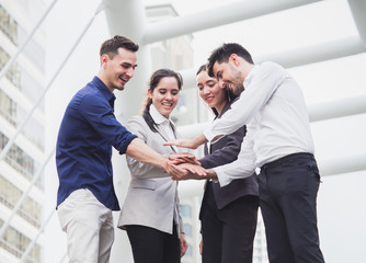 young businessman and businesswoman express teamwork, stacking hands at outdoor office