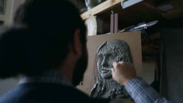 Close-up of Sculptor creating sculpture of woman's face on canvas in art studio