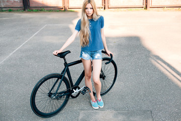 Fashion sexy blonde beautiful woman posing on the street in hot summer day with sport fixed gear bicycle