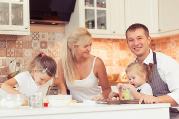 Parents and their two beautiful and cute children girls preparing breakfast ot lunch at kitchen table at home