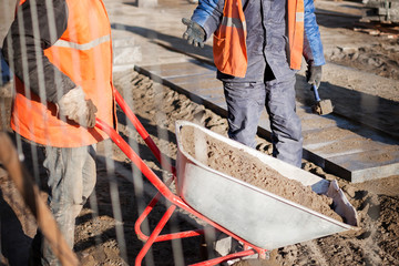 A worker is driving a wheelbarrow with sand. Repair of paving slabs
