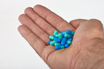 The hand of a man with different types of medication, Medicine pills or capsules in hand, palm. Colorful pills and medicines in the hand