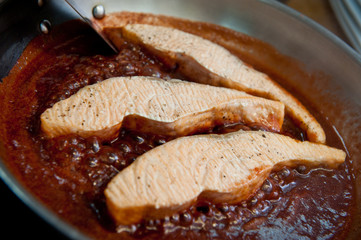 Salmon slices fried in a frying pan in sauce