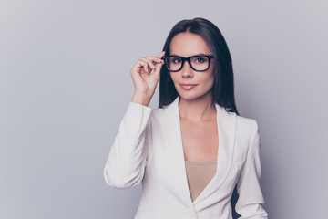 Portrait of beautiful clever gorgeous stunning charming woman with black hair wearing white  jacket, she is trying on new glasses, isolated on grey background, copyspace