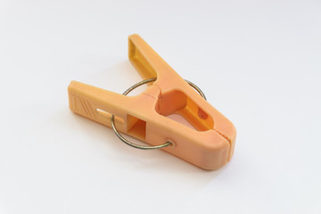 Single orange clothespin on white backgropund.