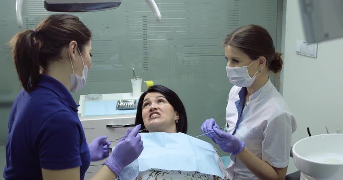 Patient at dentist with a open mouth looking on mirror ,dentist showing something