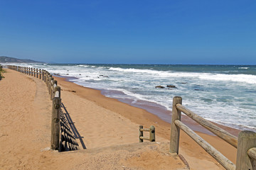 Wooden Pole Barrier on Beachfront Against Coastal  Landscape