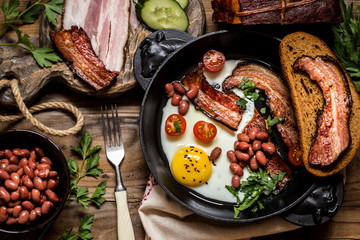 fried eggs with bacon, beans, tomatoes and herbs in a rustic style.