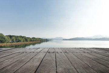 empty wooden floor with beautiful lake in blue sky