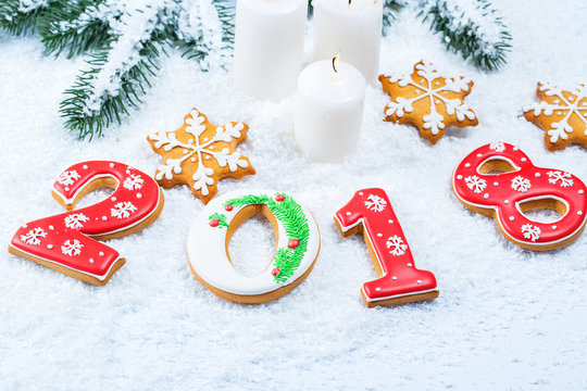 Christmas background with gingerbread cookie 2018, candle, snow and branches of a Christmas tree. Free space