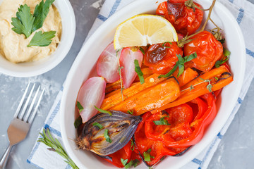 Baked vegetables: carrots, radishes, onions, tomatoes and peppers with hummus