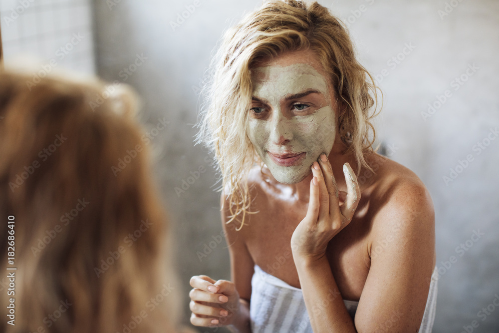 Wall mural woman looking her face in the mirror