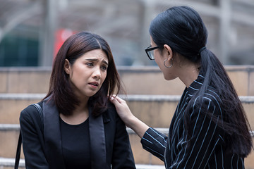 Businesswoman with hand on shoulder of colleague, consoling businesswoman stressed,suffering in the...