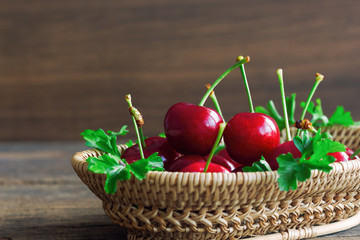 Fresh cherries on wood basket put on wooden table in side view with copy space. Cherry have high vitamin and have sweet and sour taste. Fruit background and wallpaper concept.