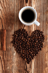 Heart shape made from coffee beans on wooden surface.