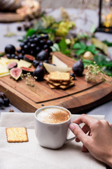 Hand holds cup of coffee with food in background