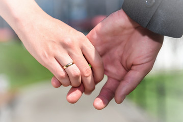 Closeup of bride and groom showing wedding rings touching hands