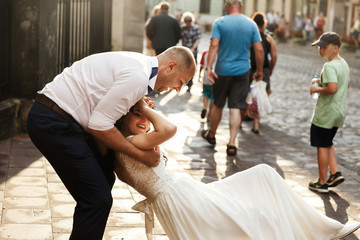 Cheerful adult wedding couple walks around the city in a sunny day