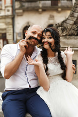 Beautiful bride and groom sit on the fountain somwhere in the old city