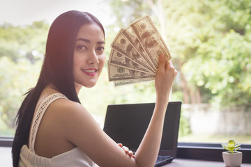 Happy face of Asian woman sitting in her home working with a laptop,Make money on the Internet as a Financial concept