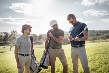 Golf player walking and carrying bag on course during summer game golfing